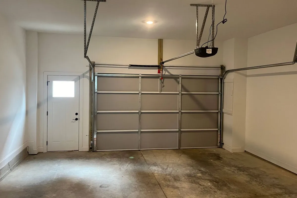 A functional garage space with both a garage door and entry door visible, providing ample room for parking vehicles and storing tools or outdoor gear. The area feels secure and practical, supporting everyday needs.
