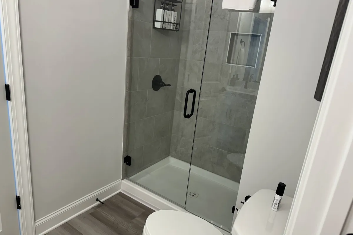 A modern, spa-inspired bathroom featuring a glass shower enclosure, minimalist decor, and a sleek faucet, offering a bright and refreshing environment for self-care and relaxation.
