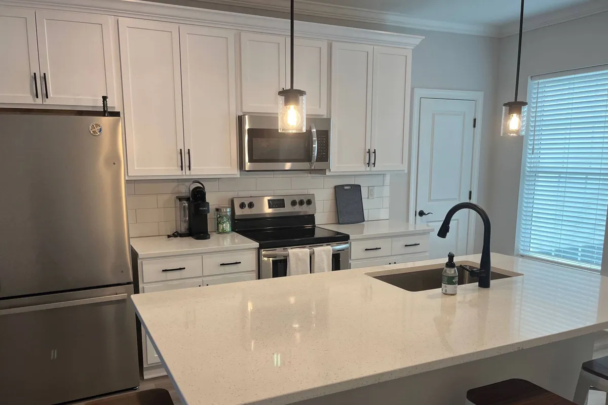A spacious, modern kitchen with a central island, stainless steel appliances, and stylish hanging light fixtures. The scene captures the room’s appeal for cooking, entertaining, and morning routines.