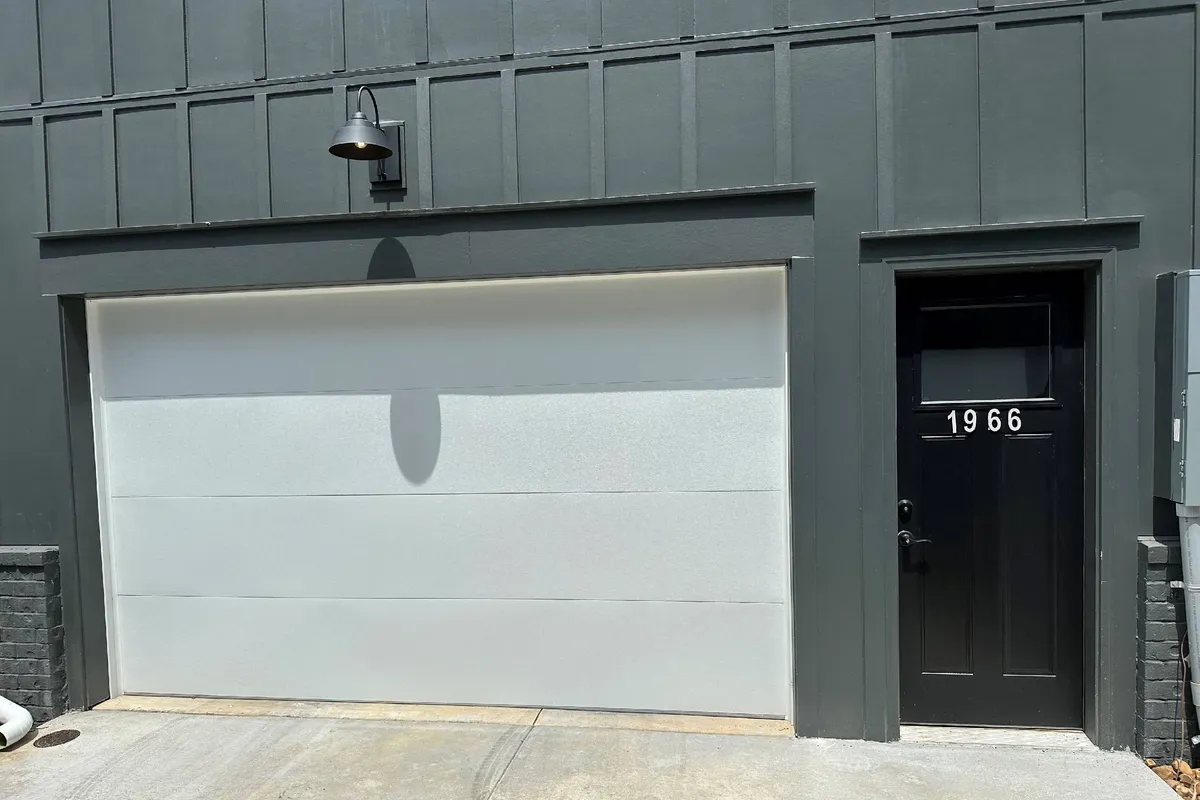 An inviting exterior view of the home, showcasing the garage door, front door, and house number. The scene conveys a sense of welcome and accessibility, with easy access for vehicles and guests alike.
