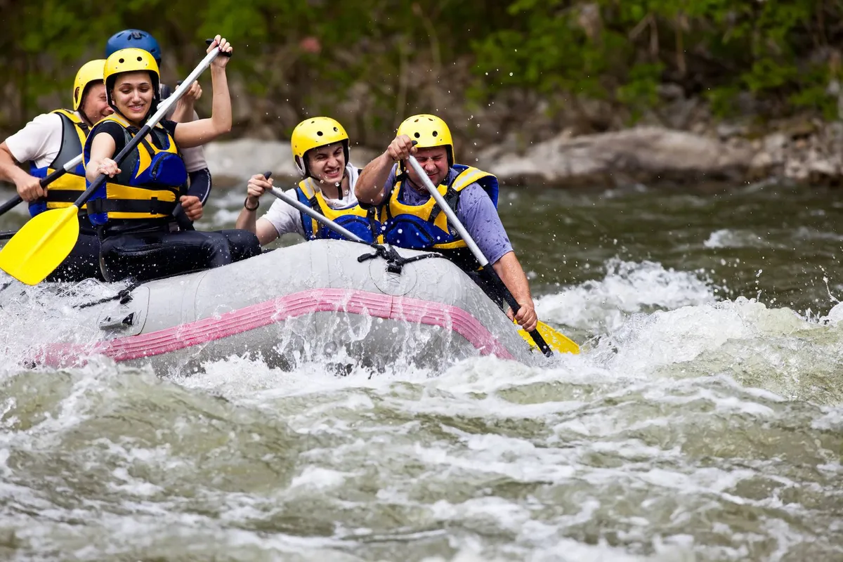 A lively group of people in a raft, paddling together through river rapids, set against a backdrop of nature. The moment captures excitement and teamwork.