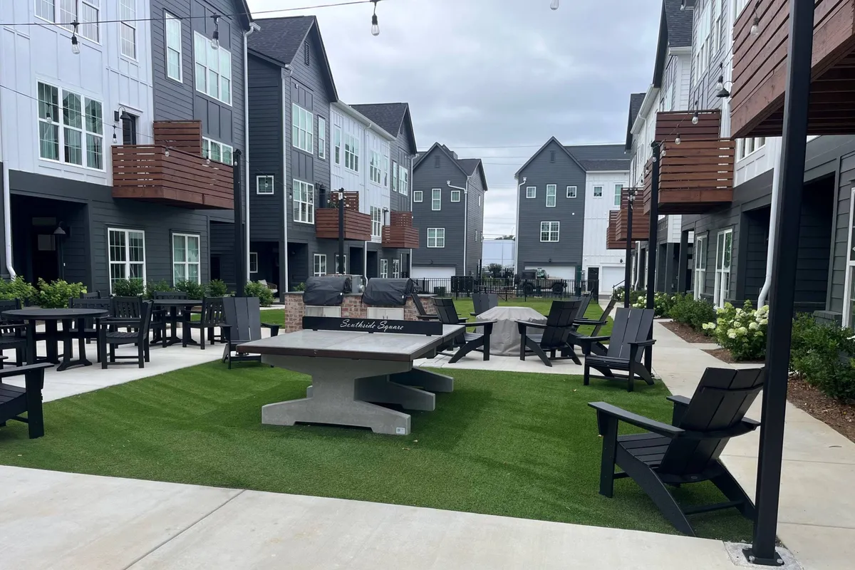 The photo highlights a spacious outdoor seating area with gathering tables set on a green lawn. The scene is prepared for social gatherings, outdoor dining, and relaxed community engagement, with a focus on comfort and togetherness.